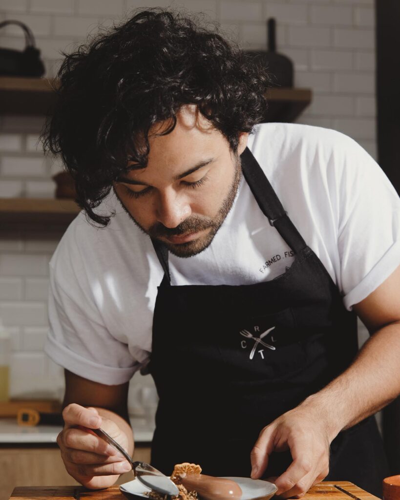Chef gilberto briceño carefully decorating a dessert, showcasing his artistic culinary skills.