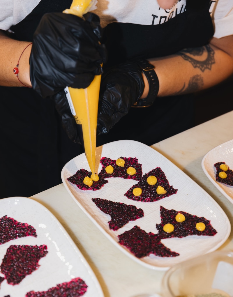 Chef carefully decorating plates with vibrant yellow sauce on artistic food arrangements.